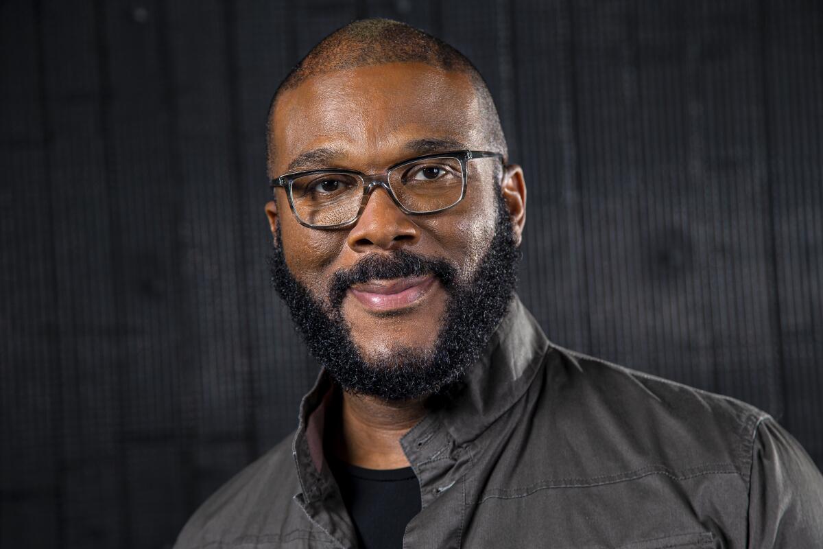 A man with a beard posing in glasses and a gray collared shirt