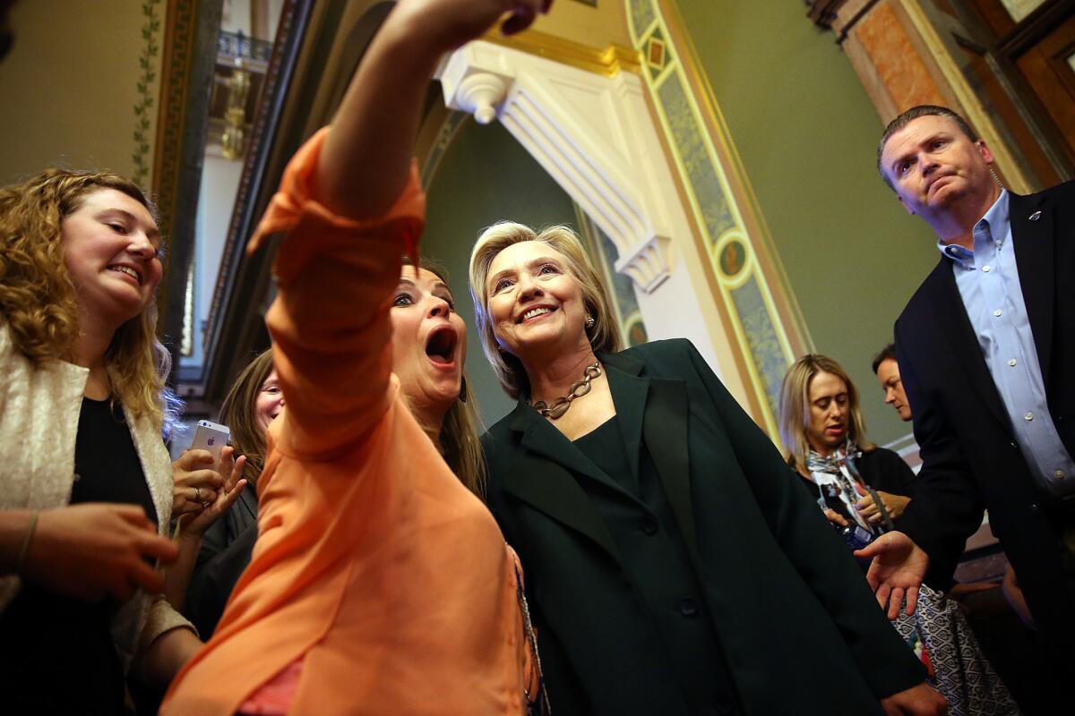 Hillary Rodham Clinton poses for a fan's selfie at the Iowa state Capitol in Des Moines. Her attempt to run a campaign with populist appeal is hitting an awkward patch as her record of promoting a proposed Pacific trade pact brings up bitterness on the left.