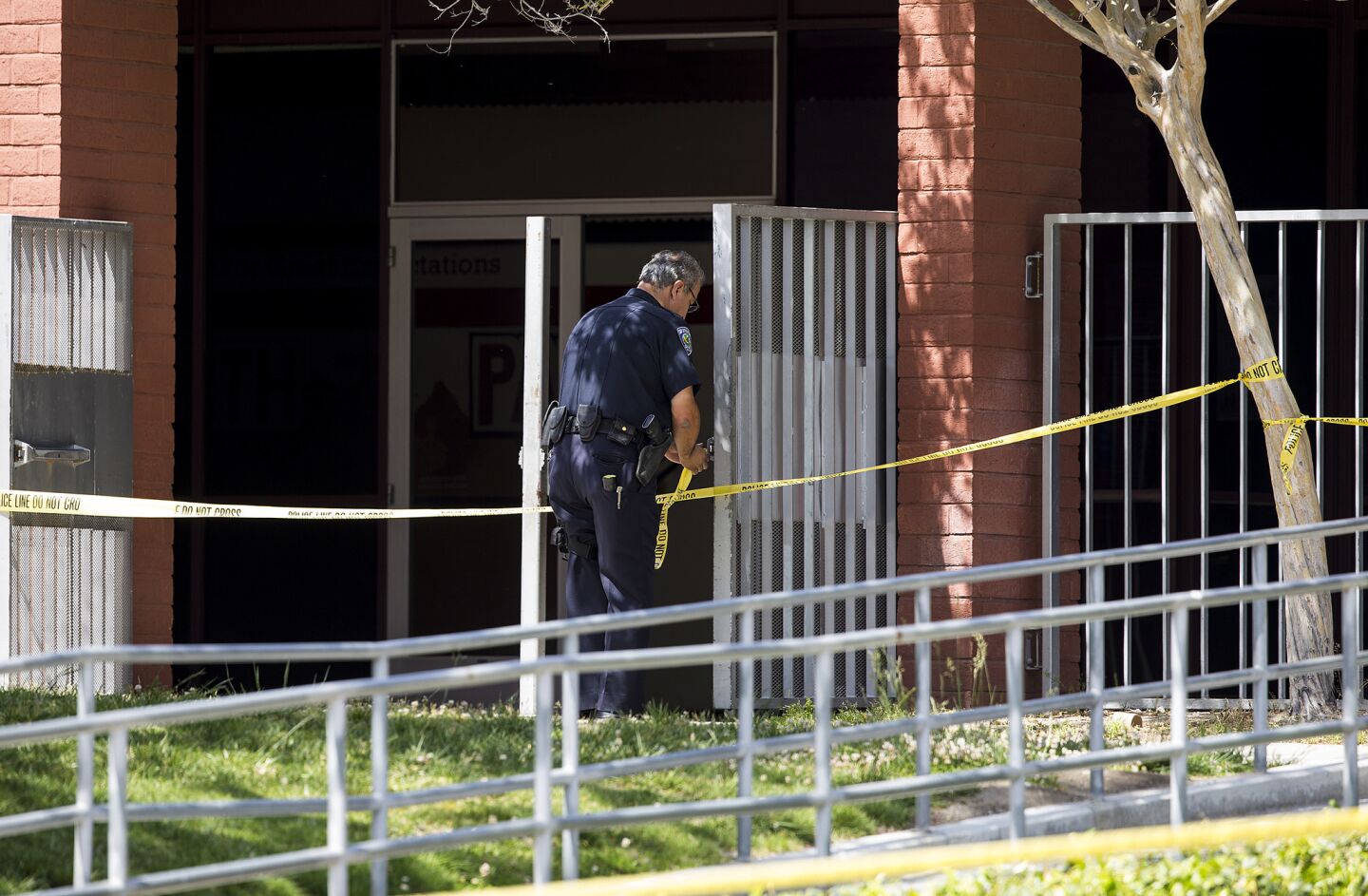 A San Bernardino police officer puts up crime scene tape after a shooting inside North Park Elementary School in San Bernardino.