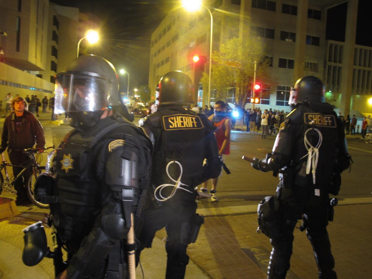 Riot police stand guard in front of protesters in downtown Albuquerque, N.M., Sunday night. **