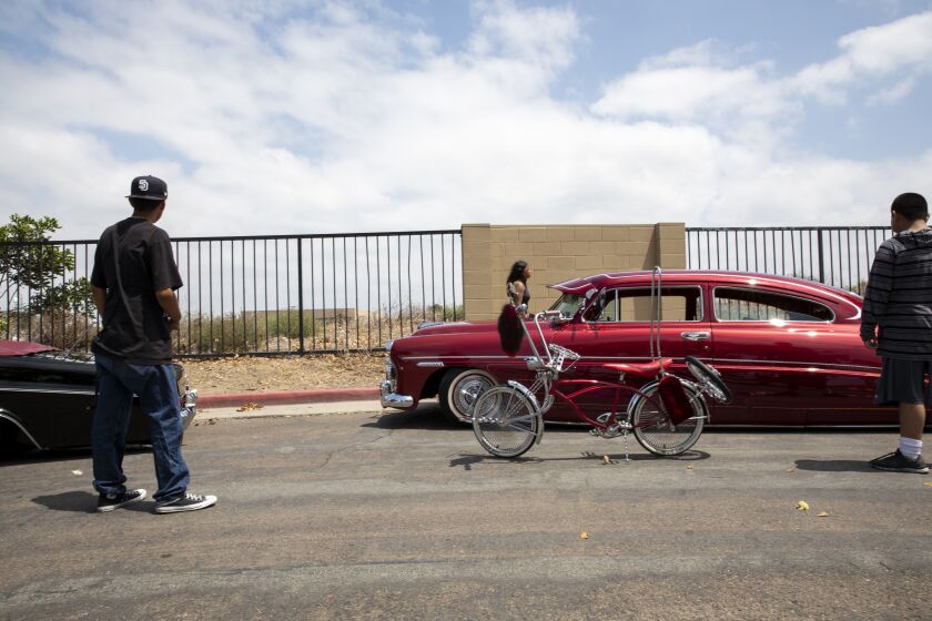 Chula Vista, CA - August 21: From left, Isaac Rosales, 16, moves his lowrider bicycle next to a 1949 Hudson Brougham for a photo as Roger Perez, 13, watches at Chula Vista Bayside Park on August 21, 2021. (Ana Ramirez / The San Diego Union-Tribune)