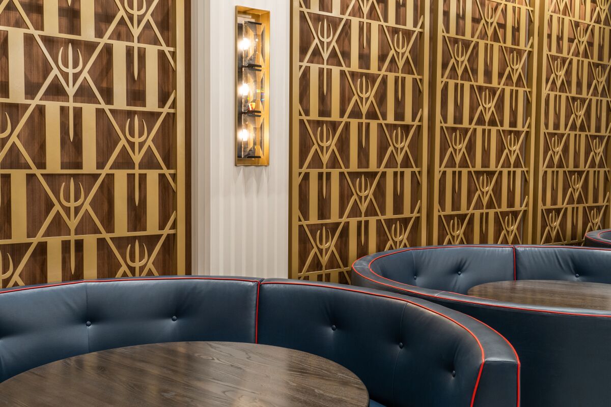 Round banquette tables line a pitchfork-decorated wall at Hell's Kitchen restaurant.