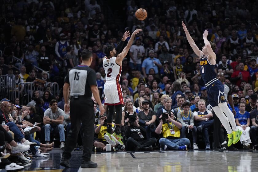 Miami Heat guard Gabe Vincent (2) shoots a 3-point basket over Denver Nuggets guard Christian Braun, right, during the second half of Game 2 of basketball's NBA Finals, Sunday, June 4, 2023, in Denver. (AP Photo/Mark J. Terrill)