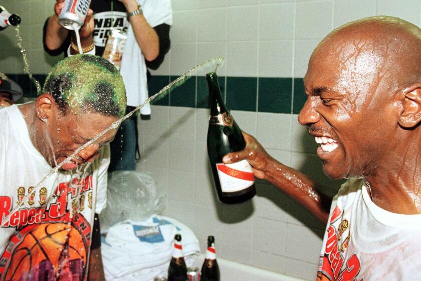 SALT LAKE CITY, UNITED STATES: Dennis Rodman (L) of the Chicago Bulls gets beer and champagne poured on his head by teammate Michael Jordan (R) and others 14 June after winning game six of the NBA Finals against the Utah Jazz at the Delta Center in Salt Lake City, UT. The Bulls won the game 87-86 to take their sixth NBA Championship. AFP PHOTO/Mike NELSON (Photo credit should read MIKE NELSON/AFP via Getty Images)