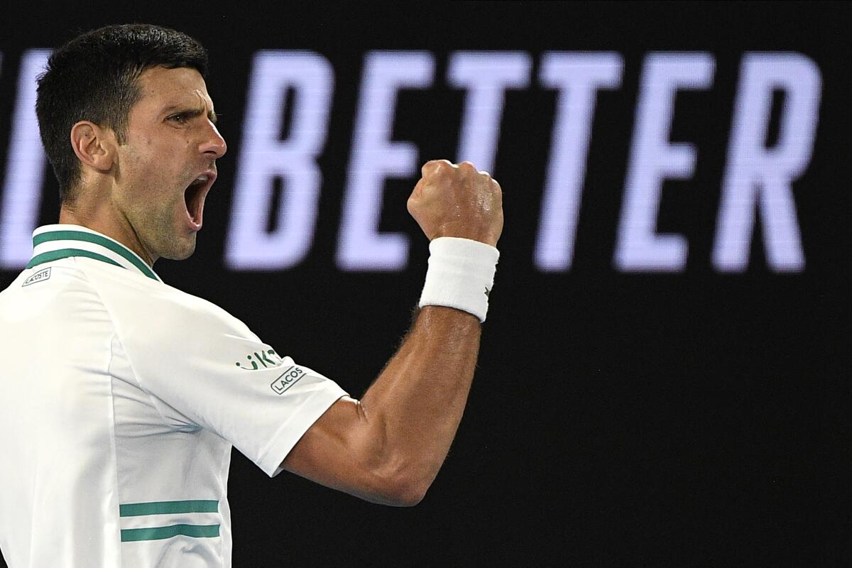 Novak Djokovic clenches a fist and yells in celebration.