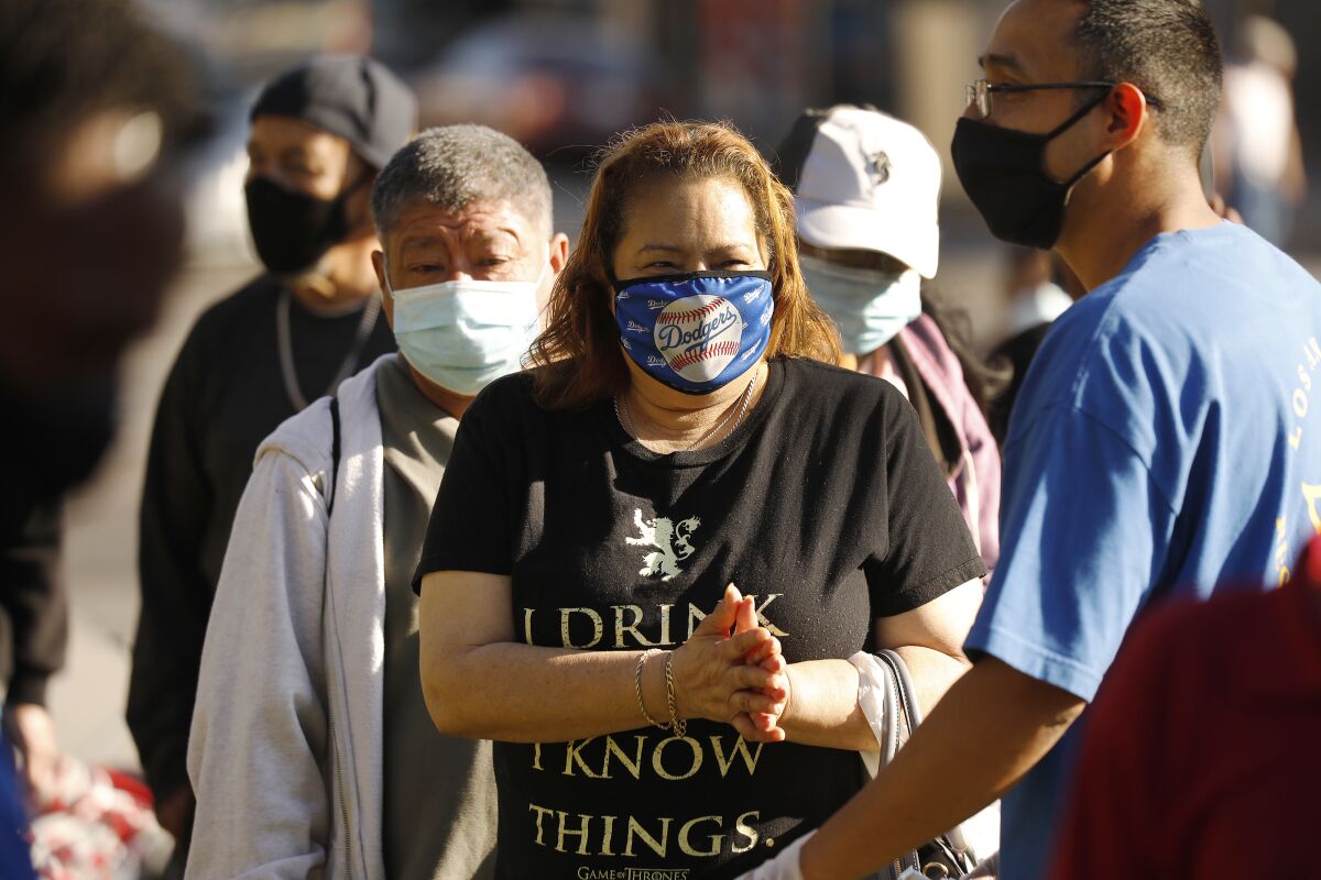 People wait in line for food distribution by Los Angeles Restoration Church on Thursday at MacArthur Park.
