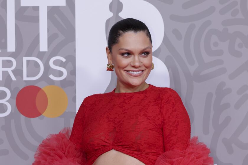 Jessie J poses wears a red lace ensemble with a cutout revealing her pregnant stomach. 