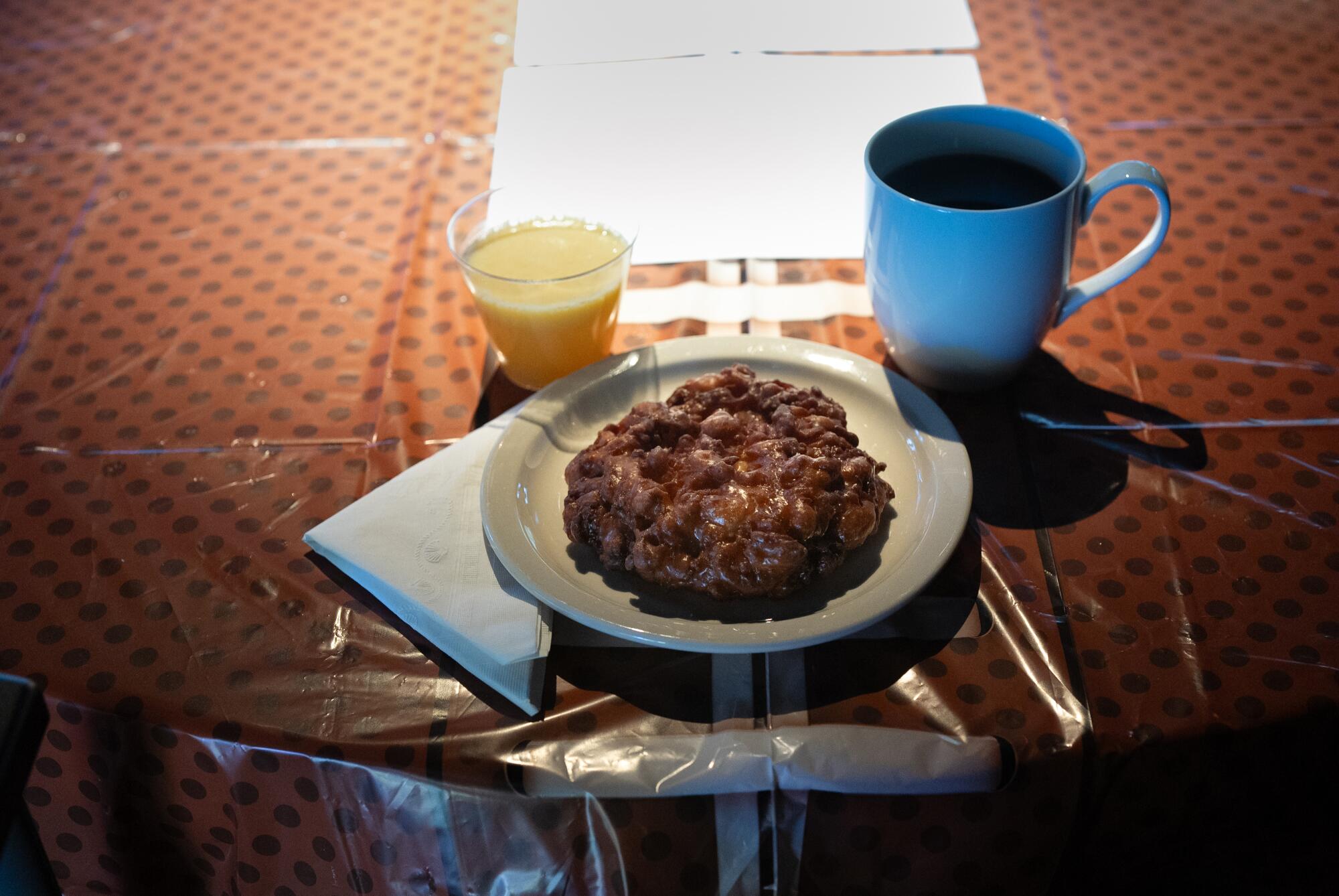 Una taza de café, zumo de naranja y bollería sobre la mesa.