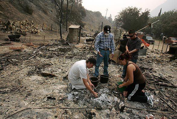 Jose Palio, left, searches with friends through the rubble of his home after the Station fire raged through Big Tujunga Canyon. Palio, who has lived in the Stonyvale neighborhood for eight years with his four children, returned for the first time Wednesday to survey the damage.