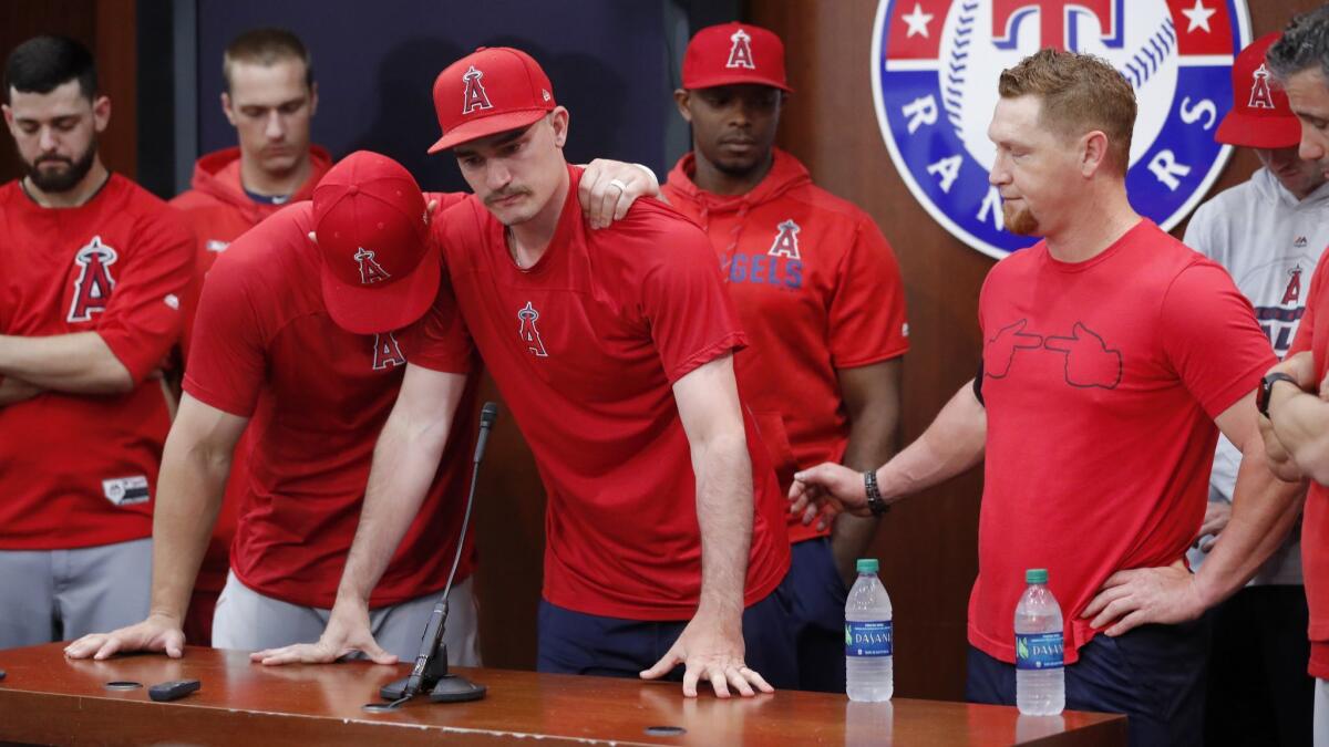 Angels' Mike Trout, left, embraces Andrew Heaney, center, who fights back tears as he answers questions about his friend and teammate, Tyler Skaggs, after a game against the Texas Rangers in Arlington, Texas on Tuesday.