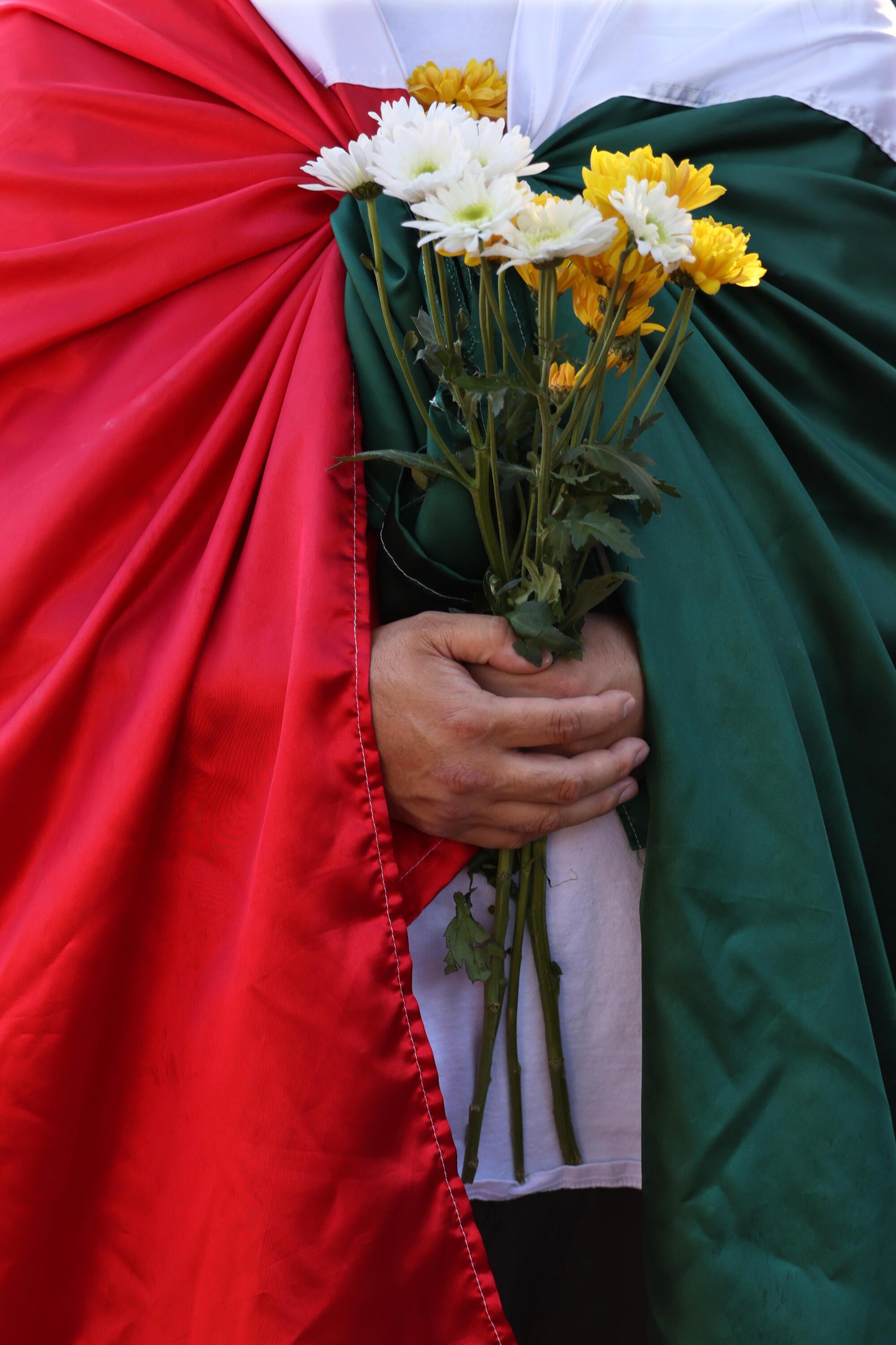 LMU student Claudio Rodriguez holds flowers while joining the family unity preayer walk.