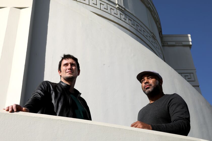 LOS ANGELES , CA - OCTOBER 26: "The Great Grass Race," show creator Denis Oliver, left, and director Cosmos Kiindariusa look toward better horizons at the Griffith Observatory on October 26, 2020. Oliver and Kiindariusa have made a success of a streaming reality competition based on David Lynch's, "The Straight Story." that sees contestants race cross-country on lawnmowers. (Genaro Molina / Los Angeles Times)