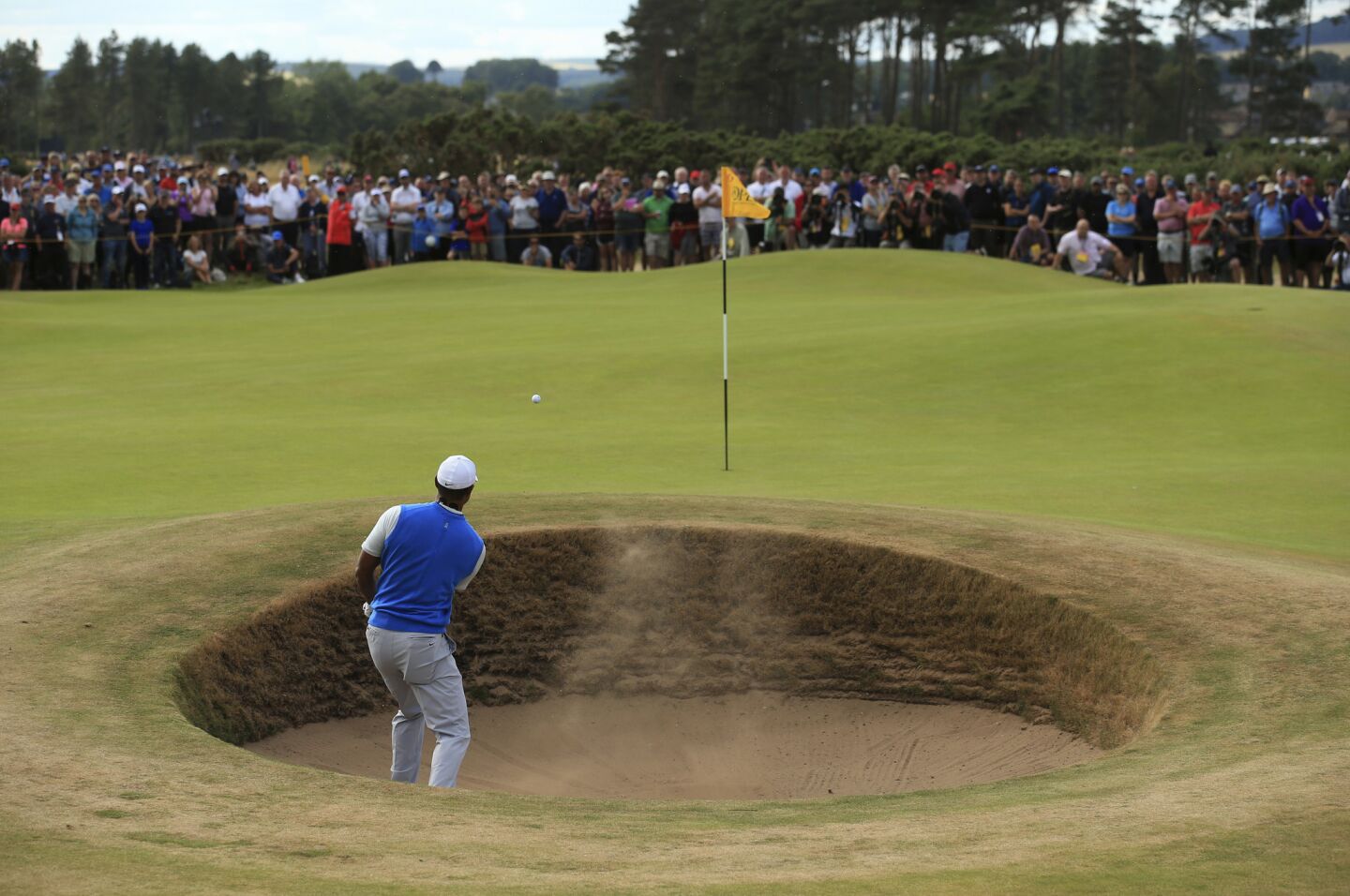 Tiger Woods plays from a greenside bunker on the sixth hole in the opening round of the British Open. Woods parred the hole and shot even par for his round.