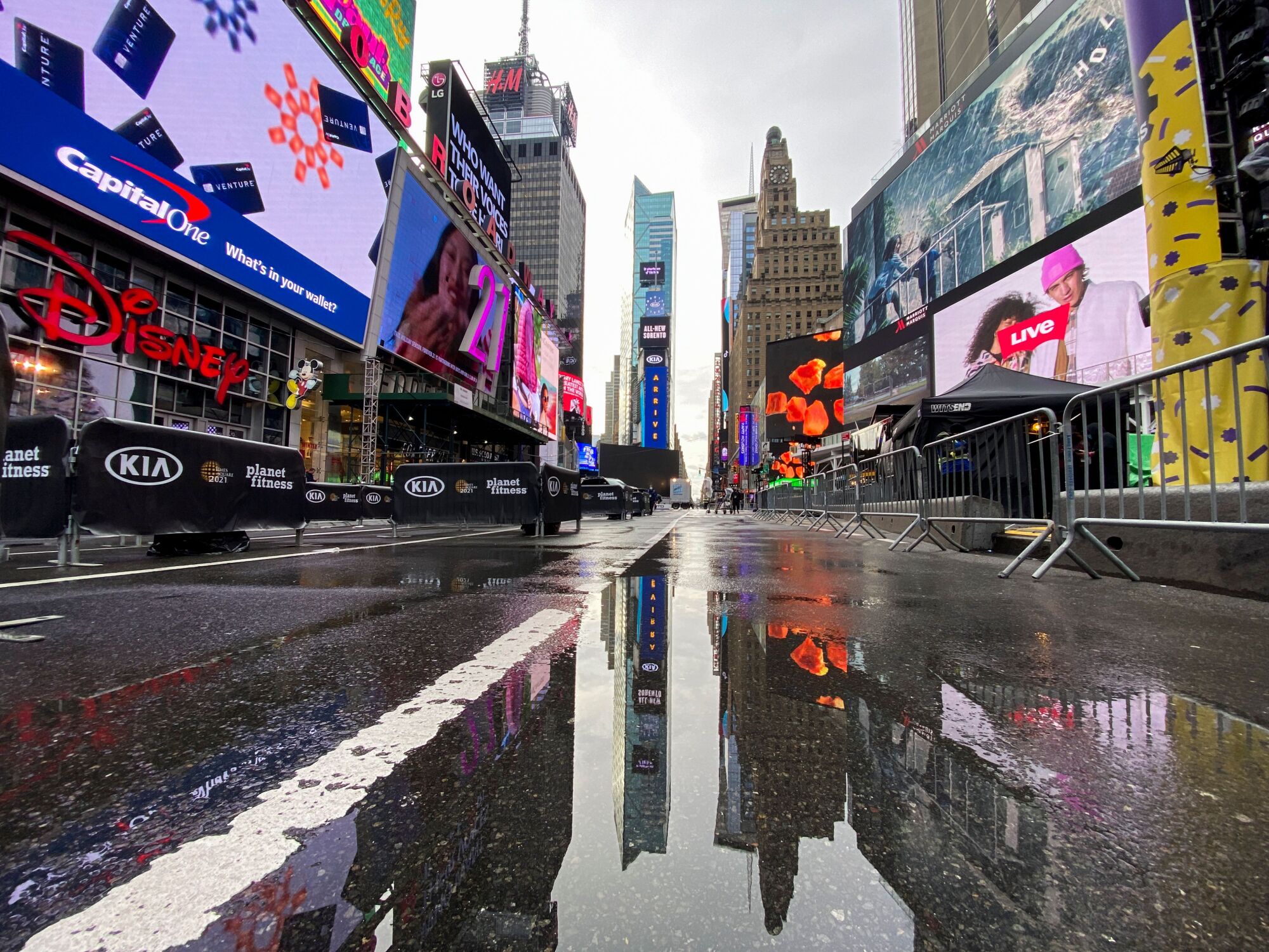 Puddles on an empty New York street reflect buildings. 
