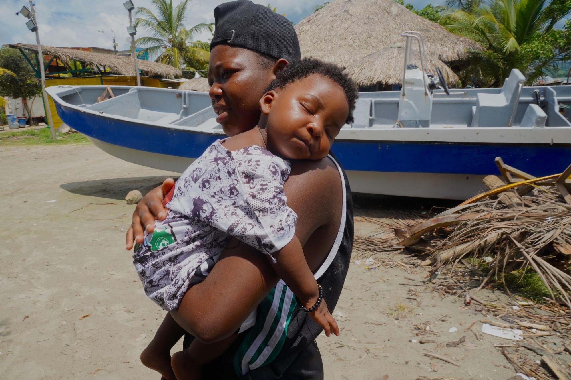 A Haitian woman holds her baby on a beach.
