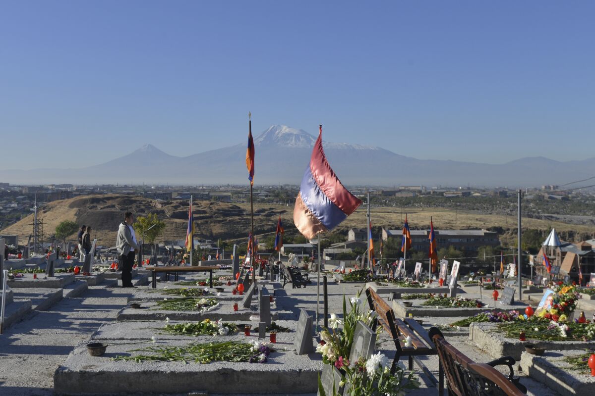 Relatives visit a military cemetery with the graves of Armenian soldiers killed during the fighting over Nagorno-Karabakh in 2020, outside Yerevan, Armenia, Monday, Sept. 27, 2021. Azerbaijan and Armenia are marking the first anniversary of the start of their six-week war in which more than 6,600 people died and that ended with Azerbaijan regaining control of large swaths of territory. In Yerevan, the Armenian capital, thousands of people went to the Yerablur military cemetery to pay respects to soldiers buried there. (Karo Sahakyan/PAN Photo via AP)