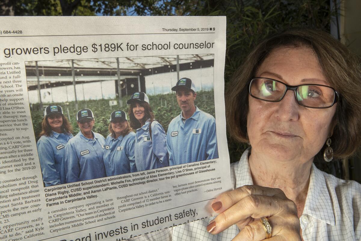 Carpinteria resident Joan Esposito holds up the Coastal View News with school board members at a pot farm