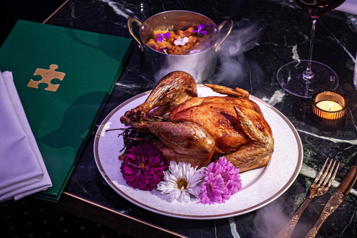 A turkey displayed on a table with wine and flower.
