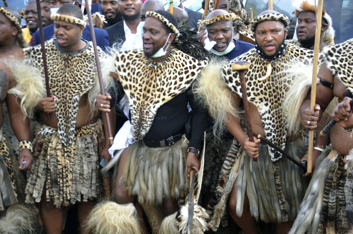 FILE - Prince Misuzulu KaZwelithin, center, flanked by fellow warriors in traditional dress at the KwaKhangelamankengane Royal Palace, during a ceremony, in Nongoma, Friday May 7, 2021. The new Zulu king can be crowned in South Africa after a court on Wednesday March 2, 2022, settled a dispute over whether Prince Misuzulu KaZwelithin named as heir to the throne last year had a rightful claim to it. (AP Photo/File)