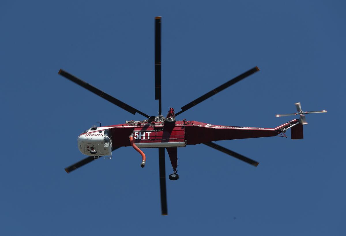 A firefighting helicopter flies over a remote area of the Arch Beach Heights neighborhood of Laguna Beach on Monday.