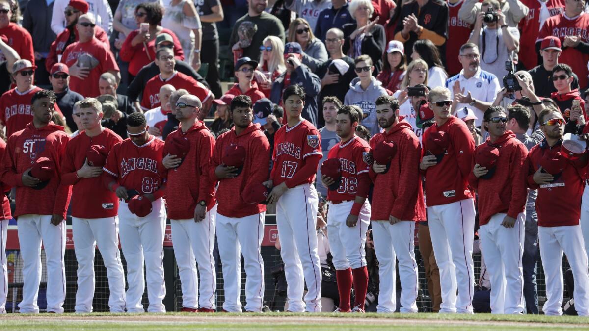 Angels players stand during the National Anthem before a game against the Milwaukee Brewers at Tempe Diablo Stadium last year in Tempe, Ariz.