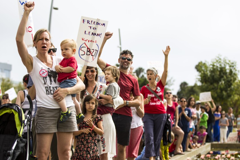 Vanessa Elliott, holding her son William, joins other opponents of the state's new child vaccination law at a rally outside Santa Monica City Hall on July 3.
