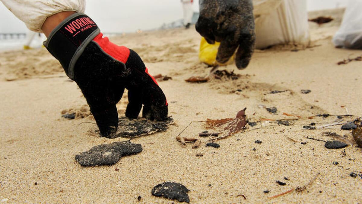 Un equipo de limpieza recoge las bolas de alquitrán que fueron arrastradas a la orilla de la playa en Manhattan Beach el jueves.