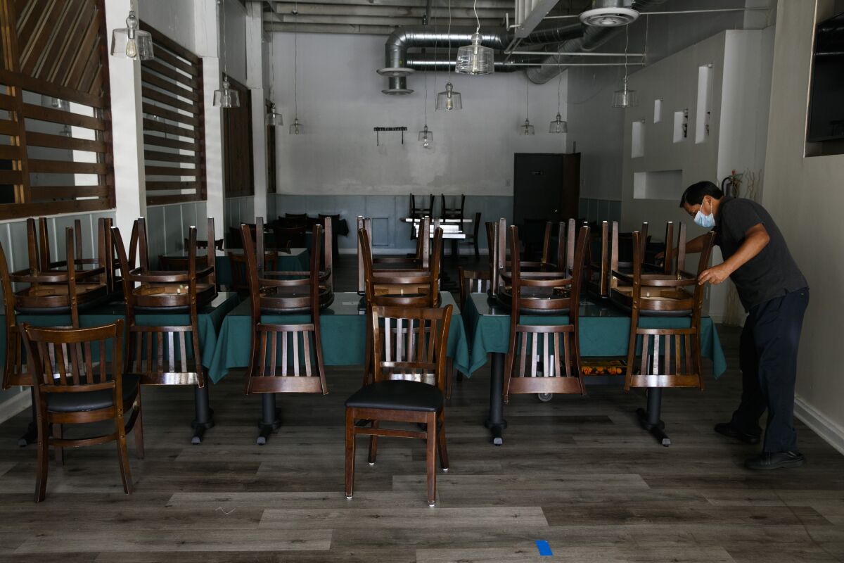 Fabian Nahui, the owner of a Peruvian restaurant, arranges chairs Monday, July 6, 2020, in Los Angeles. 