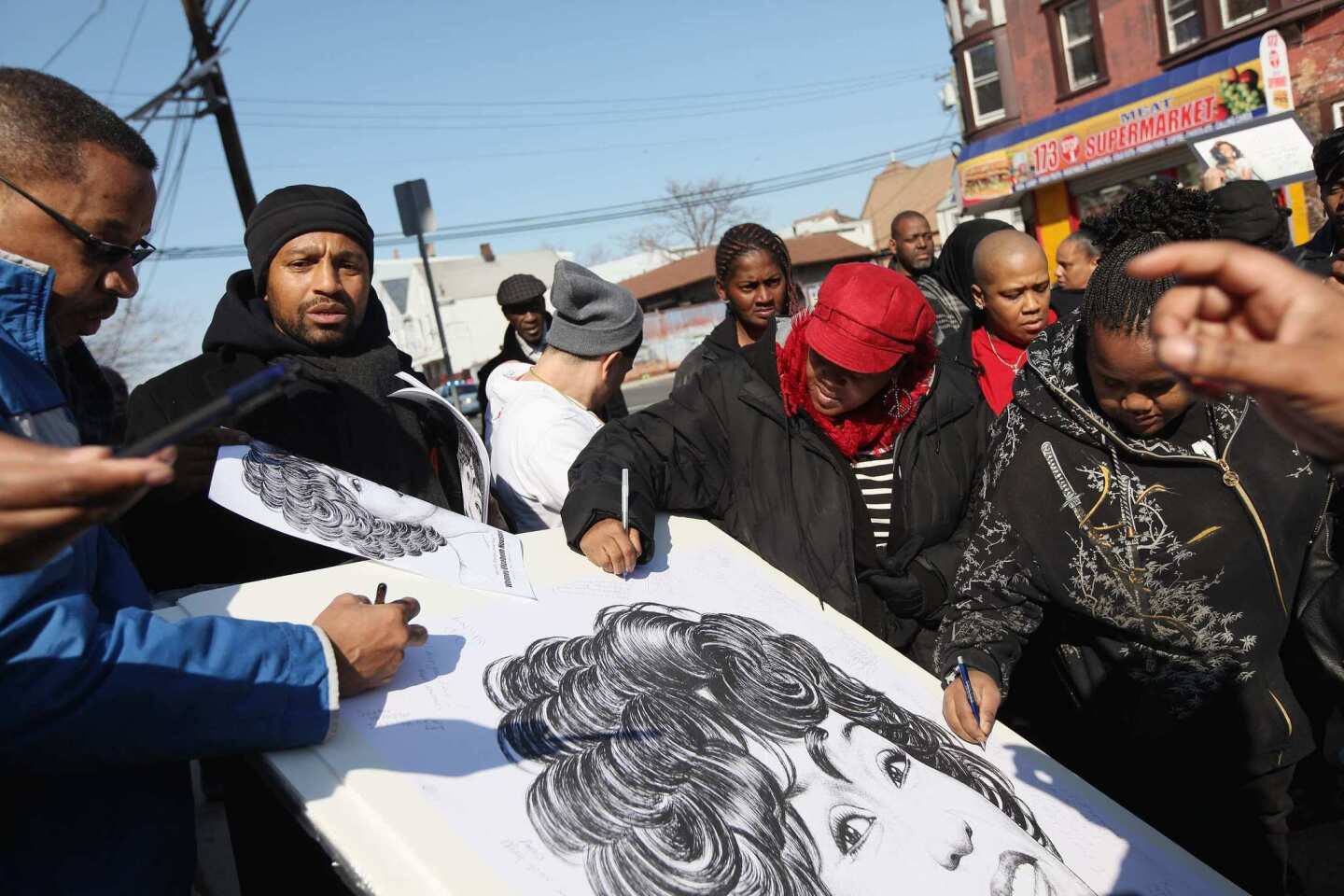 A fan signs a picture of the late Whitney Houston before her funeral in Newark, N.J. Houston died Feb. 11 in Beverly Hills.