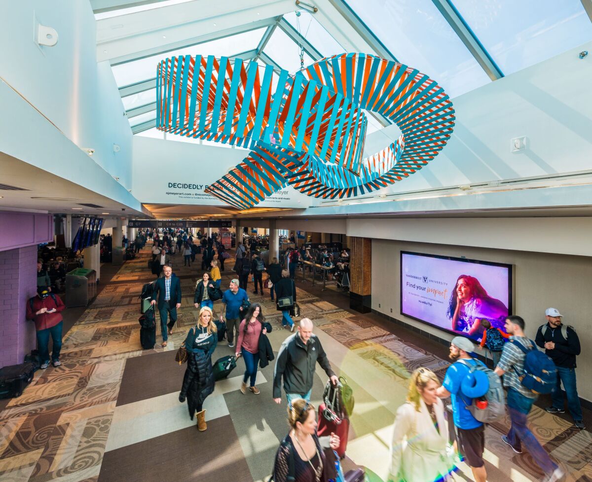 This past summer, San Diego artist Nico Meyer installed a large-scale kinetic sculpture at Nashville International Airport as part of the sixth annual Bonnaroo-themed Skylight Exhibition. Four winners were chosen for the competition, a partnership between Arts at the Airport, the Bonnaroo Works Fund and the Bonnaroo Music and Arts Festival. His sculpture “Decidedly Bonnaroo” — a 3D representation of trefoil knots — hangs high above the airport’s Concourse C, near Gate C-7.