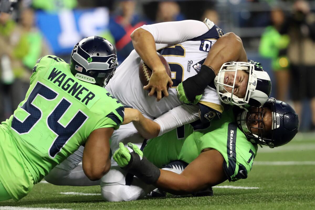 Rams quarterback Jared Goff is tackled by Seattle’s Bobby Wagner, left, and Al Woods.