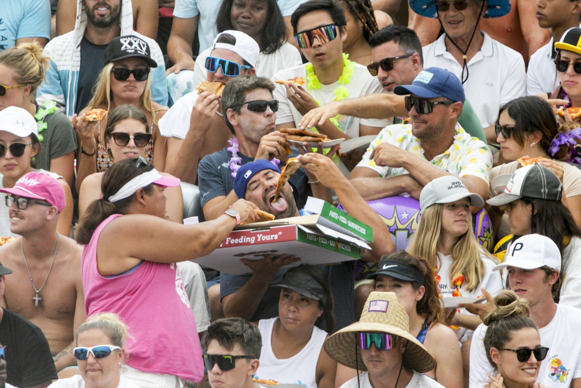 Fans enjoy pizza while watching the AVP Hermosa Beach Open final.