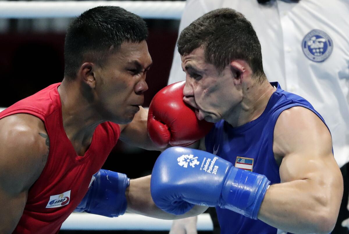 FILE - In this Friday, Aug. 31, 2018, file photo, Phillippines' Eumir Felix Marcial, left, and Uzbekistan's Israil Madrimov fight in their men's middleweight boxing semifinal at the 18th Asian Games in Jakarta, Indonesia. The International Boxing Association (AIBA) allowed professional boxers into the Olympics for the first time in Rio, but just three competed, and none did well. The COVID-affected qualification process and a general disinterest among top pros means there won't be any household names fighting in Tokyo, either. There are several pros in the field, but most, like Filipino middleweight Eumir Marcial, kept a foot in each boxing world during the pandemic. (AP Photo/Lee Jin-man, File)