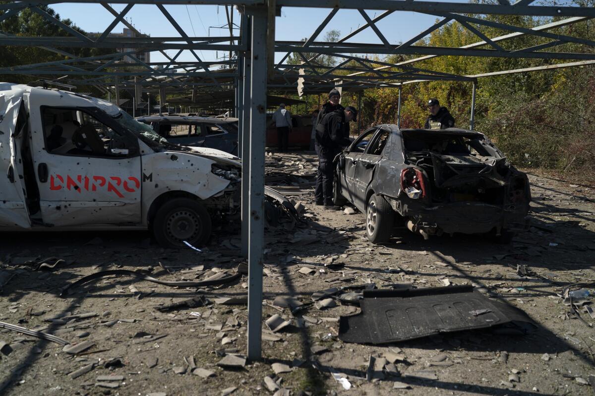 Police officers work at a site where several cars were damaged after a Russian attack.