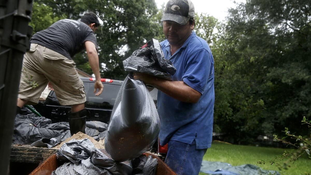 Ruben Lozano, 47, and Javier Escamilla, 27, create makeshift sandbags in an effort to ward off the surging Brazos River from their home in Reyes Trailer Park.