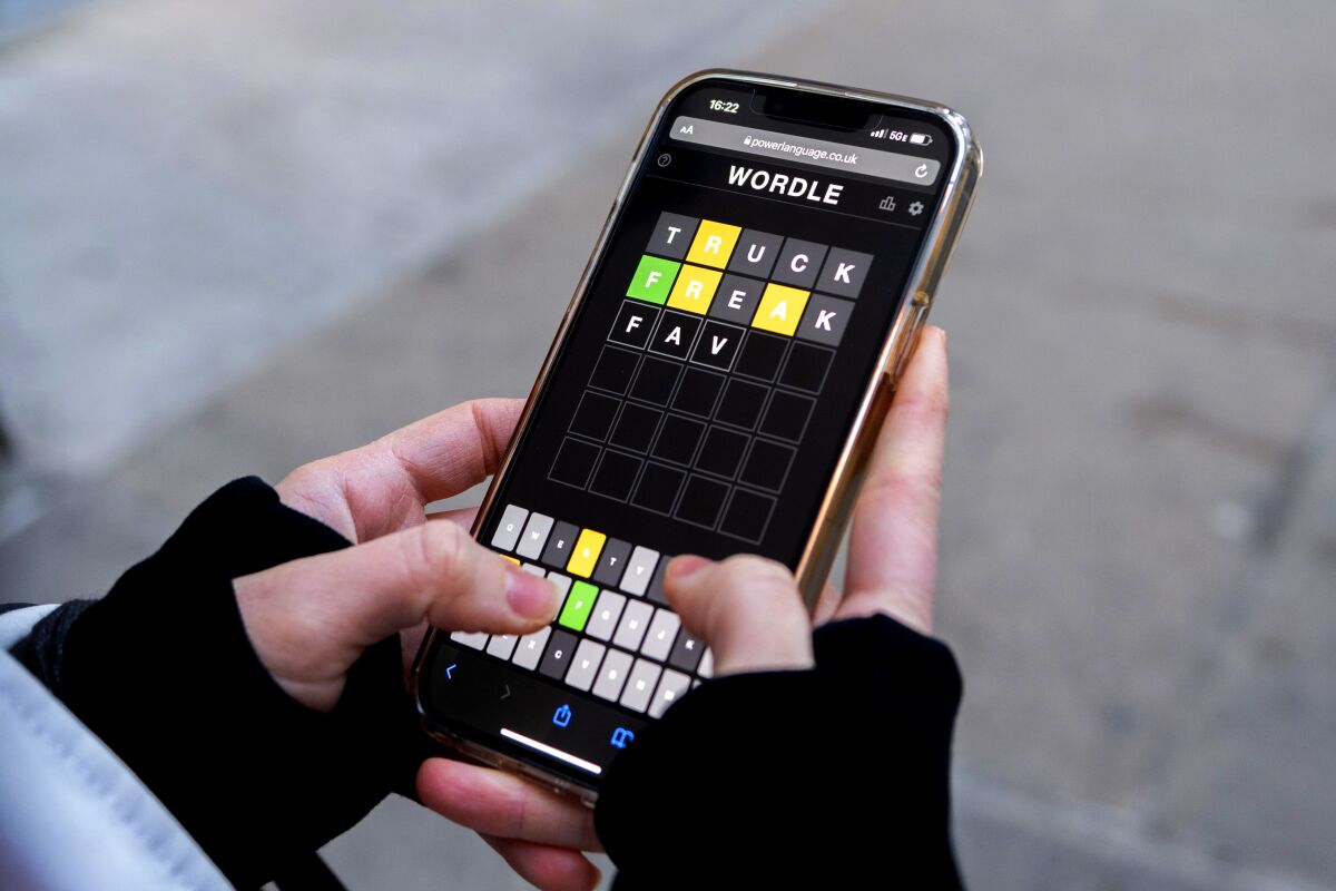Hands hold a cellphone with the game Wordle on the screen