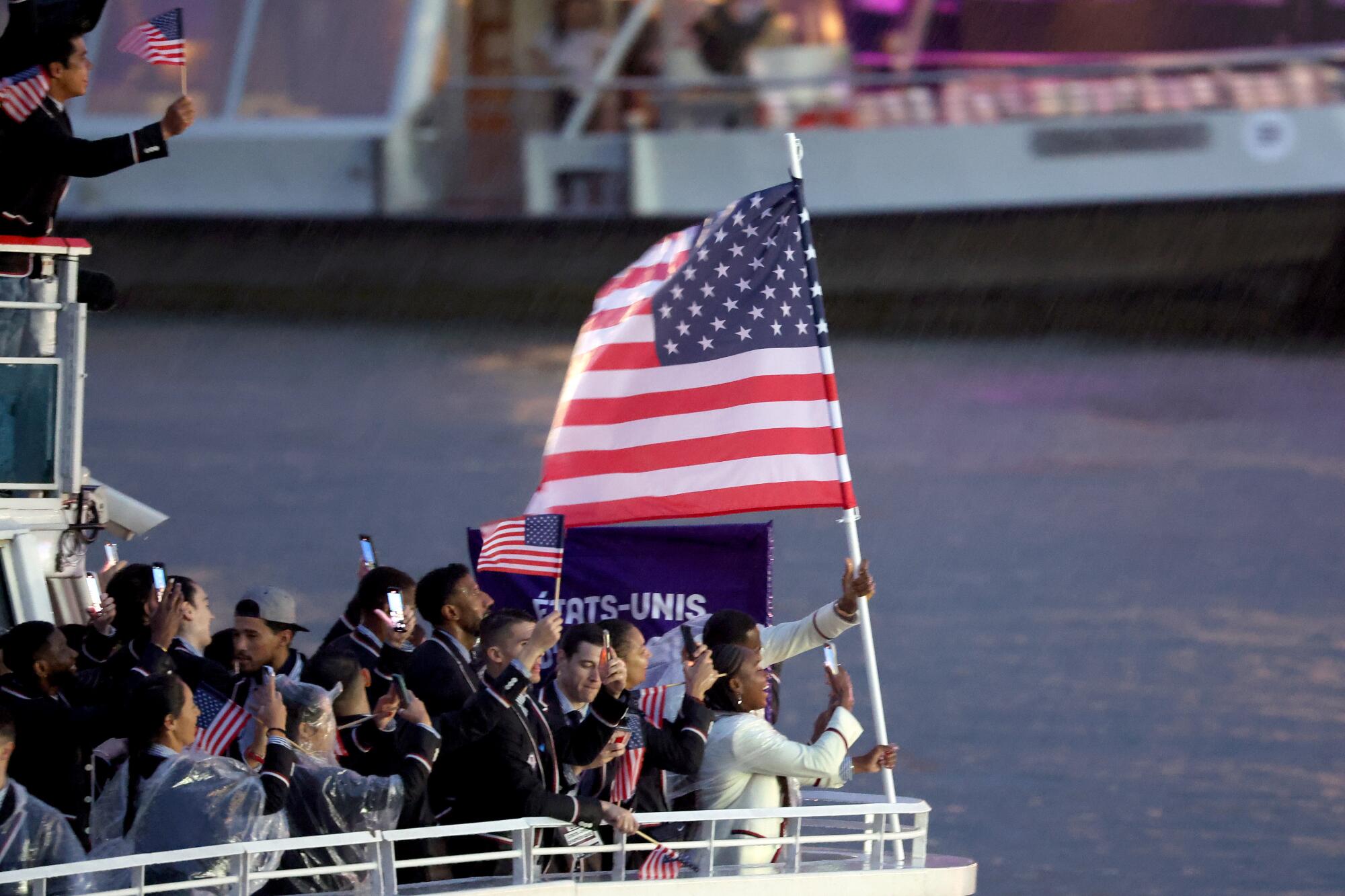 U.S. flag bearers Coco Gauff and Lebron James stand at the front of the Team USA boat as it floats down the Seine.