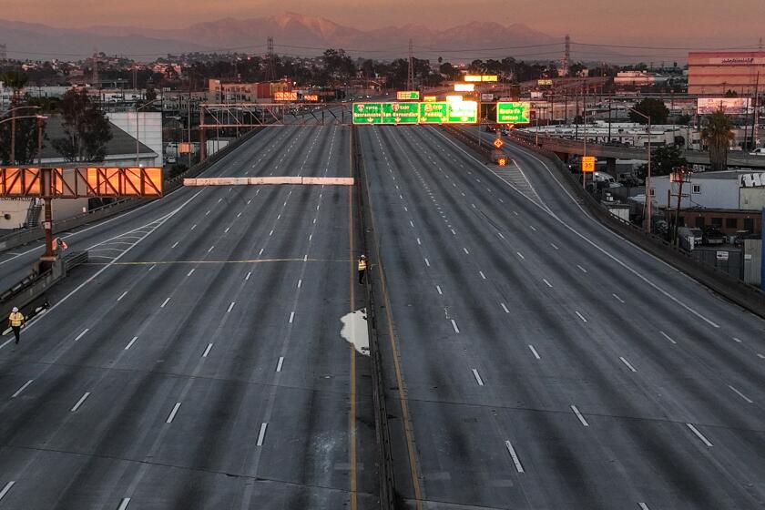 Los Angeles, CA, Monday, November 13, 2023 - CalTrans workers walk along the closed stretch of the 10 freeway days after a large pallet fire burned below, shutting the freeway to traffic. (Robert Gauthier/Los Angeles Times)