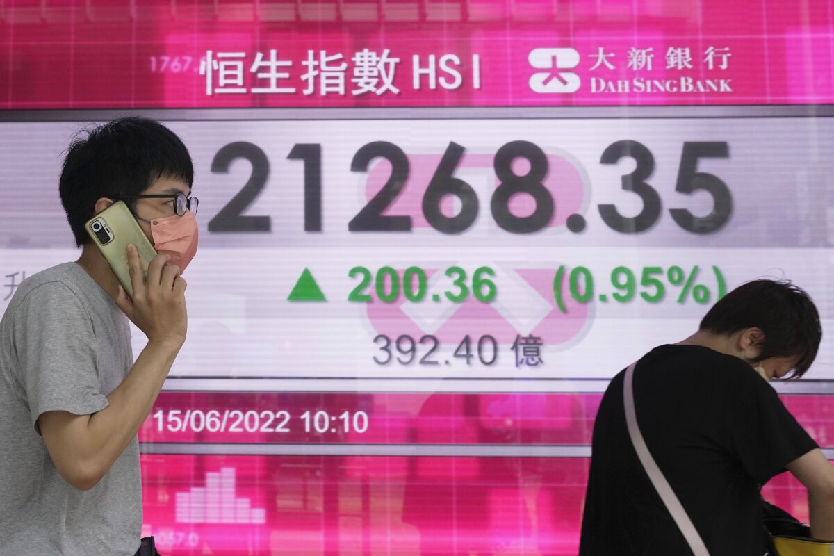 A man wearing a face mask stands in front of a bank's electronic board showing the Hong Kong share index in Hong Kong, Wednesday, June 15, 2022. Asian stock markets were mixed Wednesday ahead of the Federal Reserve's announcement of how sharply it will raise interest rates to cool U.S. inflation. (AP Photo/Kin Cheung)