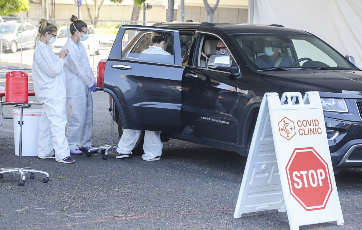 Nurses stand near an open car door as one draws blood from a passenger.