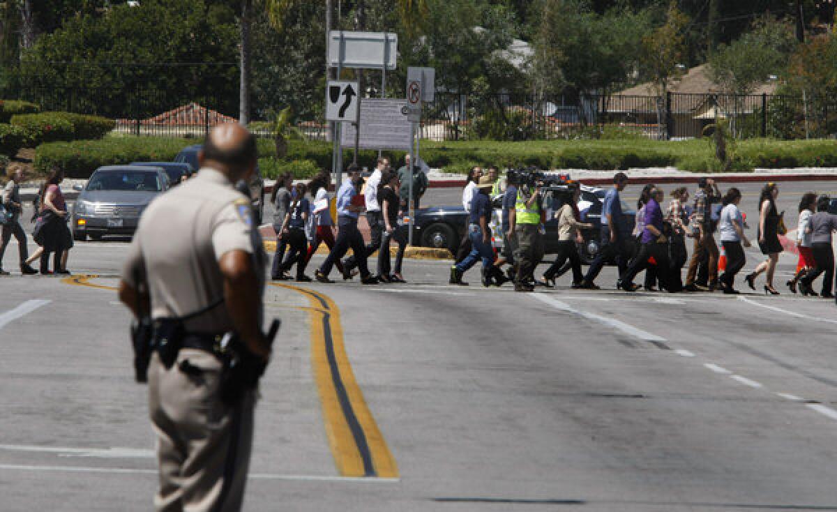 A California Highway Patrol officer watches students and teachers file across North Eastern Avenue at the entrance to Cal State L.A. after university officials evacuated the campus.