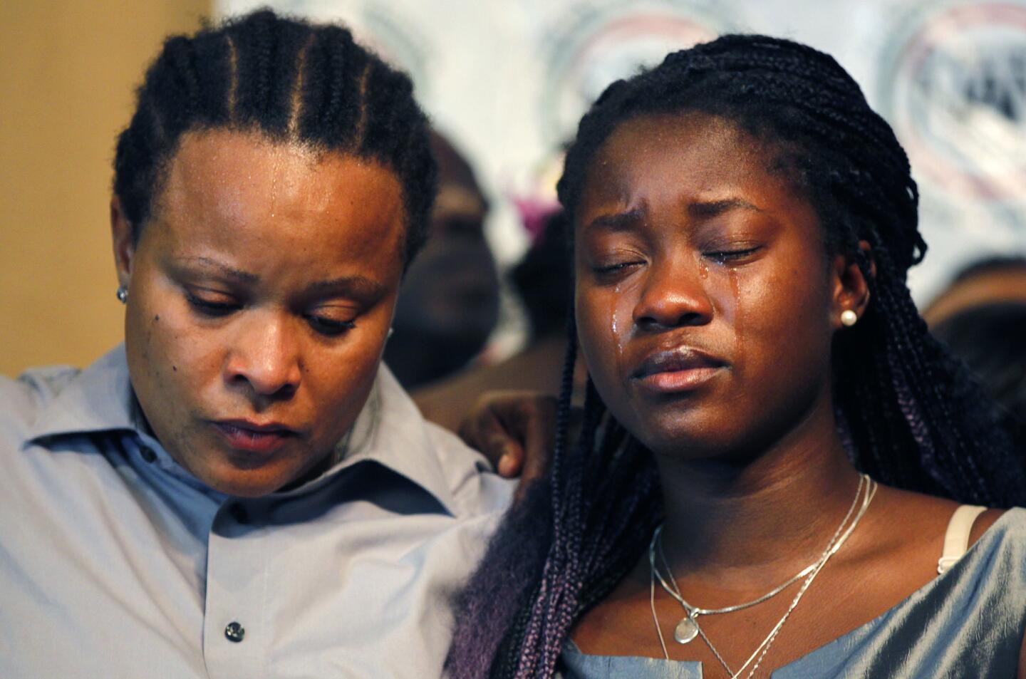 Taina Rozier, left, wife of victim Alfred Olango and daughter Charé Rozier listen during a news conference about the shooting.
