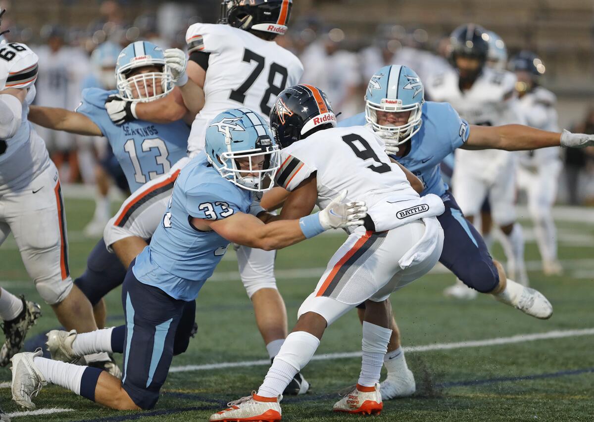 Corona del Mar defenders Dylan Wood (33) and Charlie Mannon bring down running back Sammy Green against Huntington Beach.