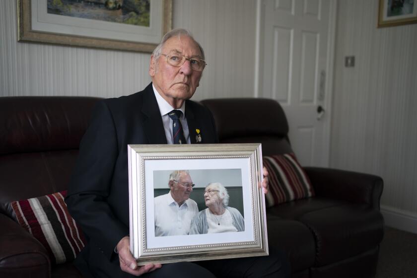 Gordon Bonner holds one of his favorite photographs of him with his late wife Muriel who, in April 2020 died of COVID-19, at his home in Leeds, England, Saturday Jan. 23, 2021. Bonner, 86, is just one of many hundreds of thousands of Britons toiling with grief because of the pandemic. (AP Photo/Jon Super)