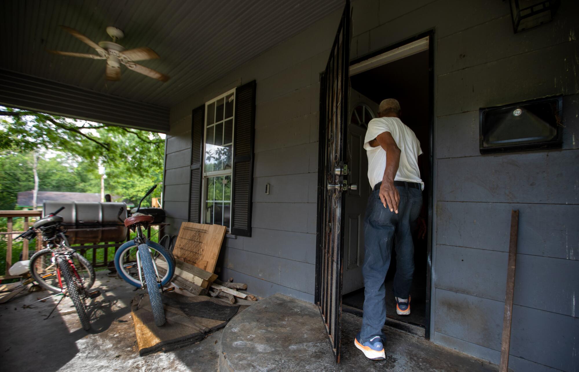 A man walks into a home with bicycles on the porch.