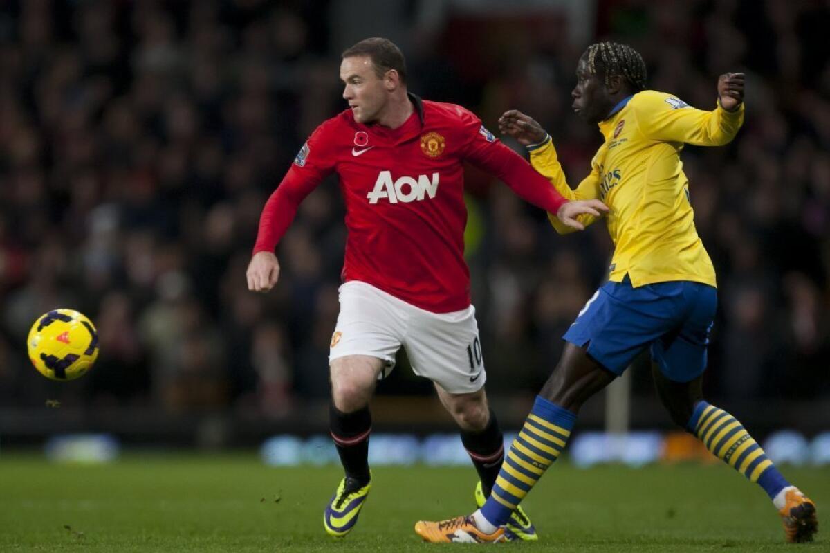 Manchester United's Wayne Rooney, left, keeps the ball from Arsenal's Bacary Sagna during their English Premier League soccer match on Sunday.