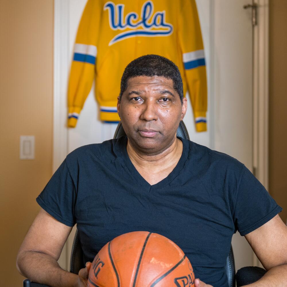 Former UCLA basketball star Rod Foster holds a basketball and sits in his wheelchair in his West L.A. home. 