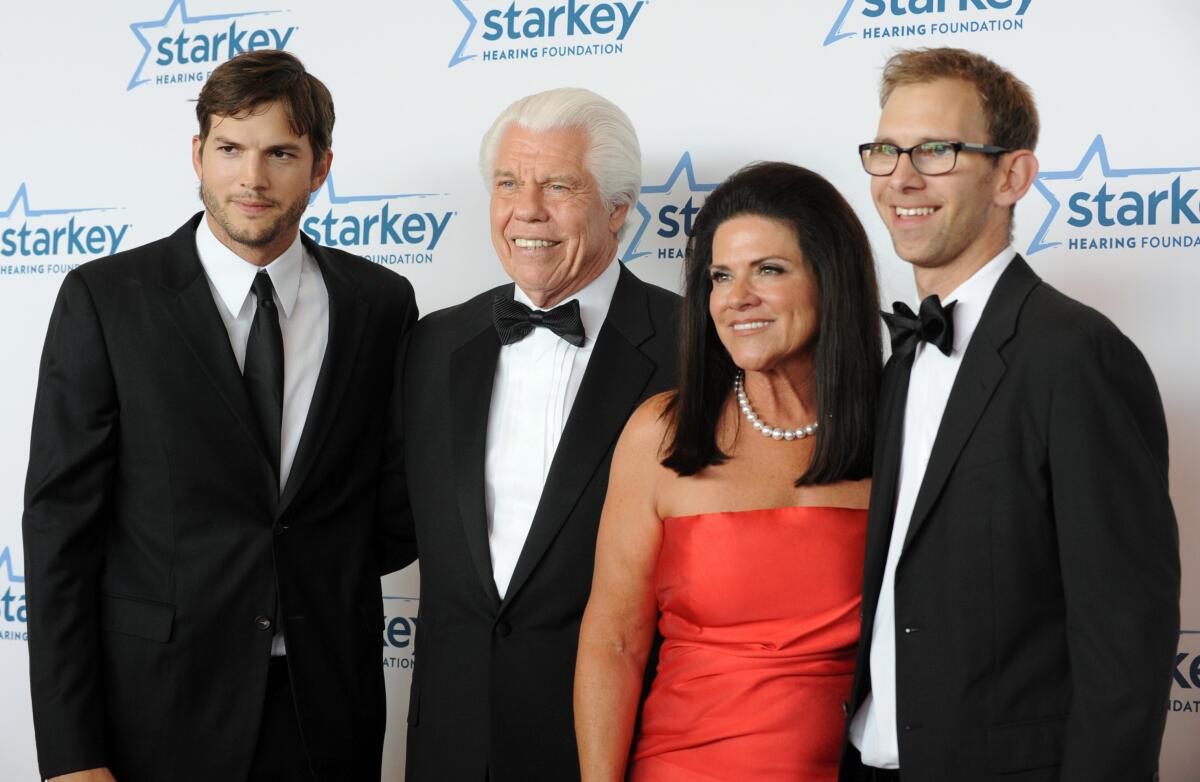 Three men and a woman posing in formalwear