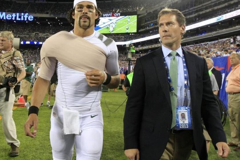 New York Jets quarterback Mark Sanchez walks off the field with Dr. Andrew Willis in August.