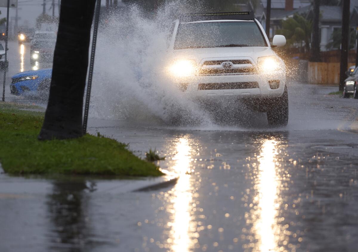 A vehicle is driven through a flooded area on Madison Ave. in North Park.